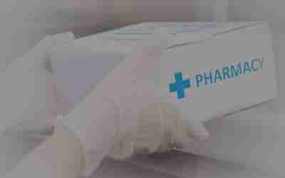 A person is holding a box with the word pharmacy on it.