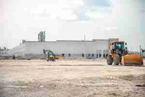 Two bulldozers in front of a large building undergoing Cold Chain modifications.