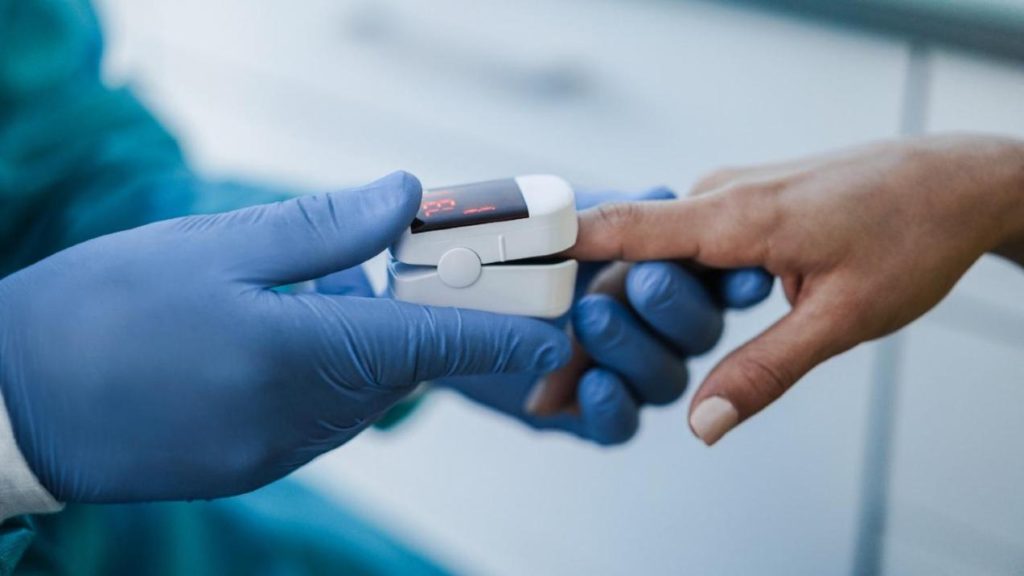 A doctor is providing a patient with a blood pressure cuff to monitor their health.