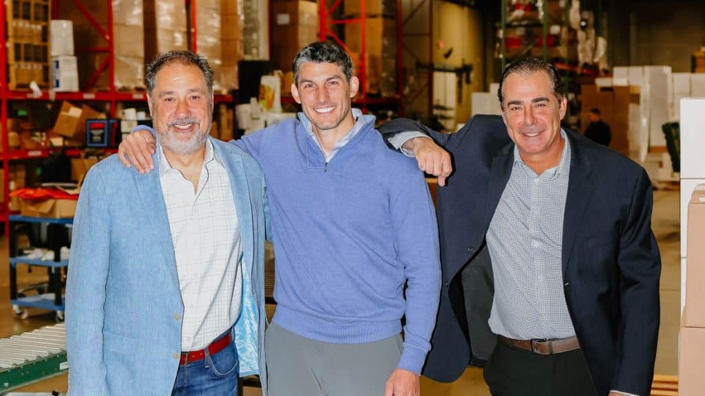 Three smiling CEOs posing together in a cold chain warehouse environment.