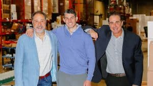 Three smiling CEOs posing together in a cold chain warehouse environment.