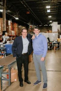 Two smiling cofounders standing together in a warehouse environment, disrupting third-party logistics.