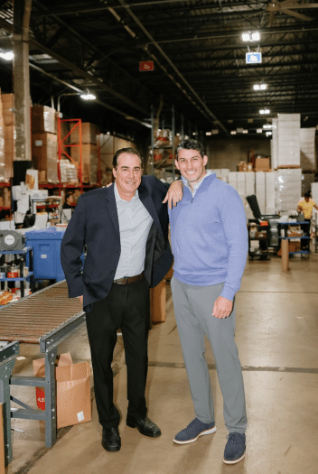 Two smiling cofounders standing together in a warehouse environment, disrupting third-party logistics.