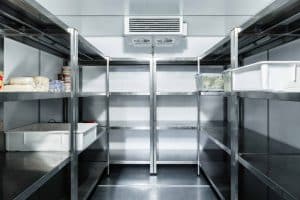 A clean, industrial-style walk-in fridge with stainless steel shelves offers cold storage solutions perfect for small businesses. This setup is partially stocked with containers and packaged food items, providing affordable options for efficient organization.