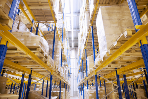 Chicago cold storage facility features a warehouse interior with tall blue and yellow shelves stacked with palletized boxes on both sides of a bright aisle.