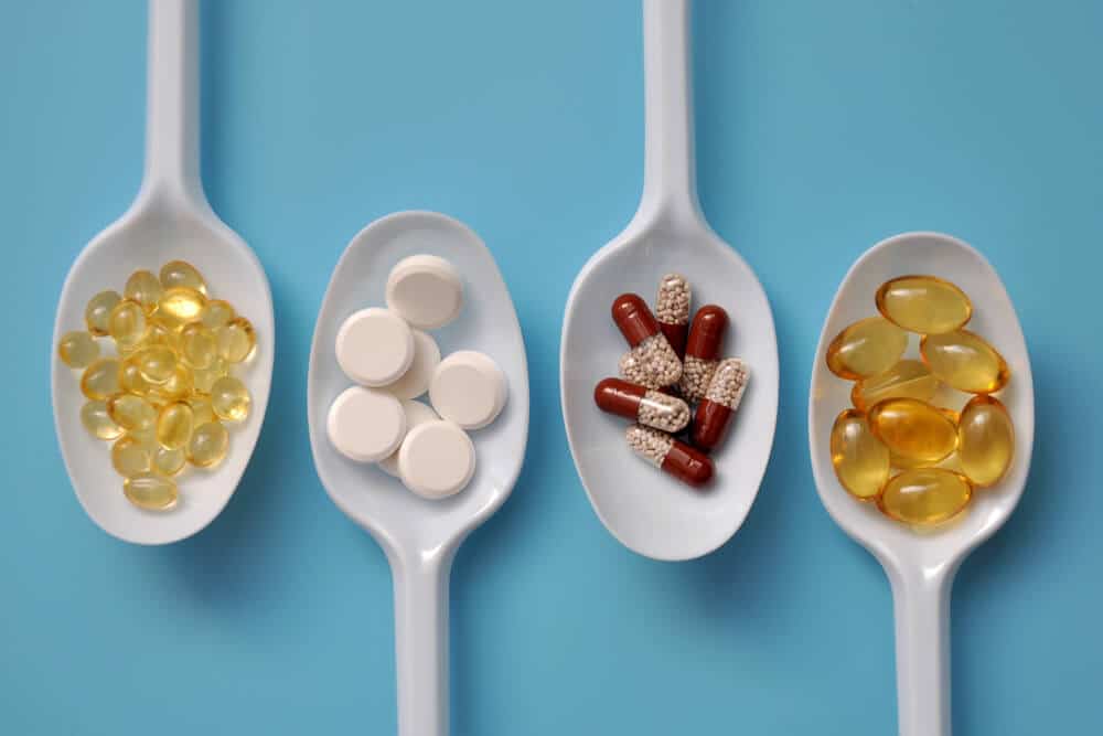 Four white spoons each contain a different type of pill or capsule, displayed on a blue background—much like how NetSuite Fulfillment Solutions offer diverse options for seamless order fulfillment for NetSuite users.